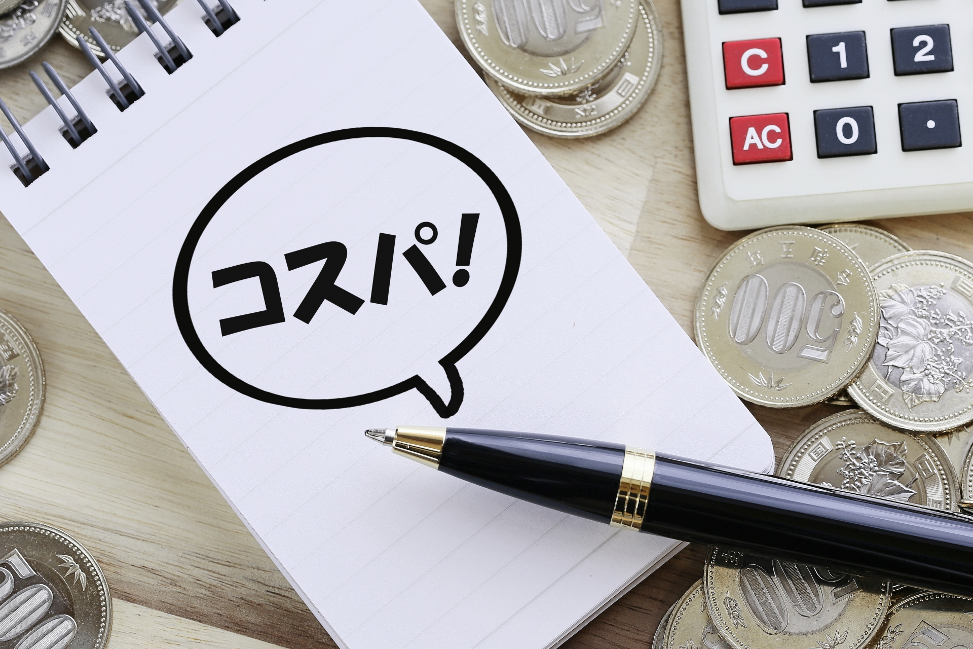 コストパフォーマンスを示すメモと硬貨と電卓