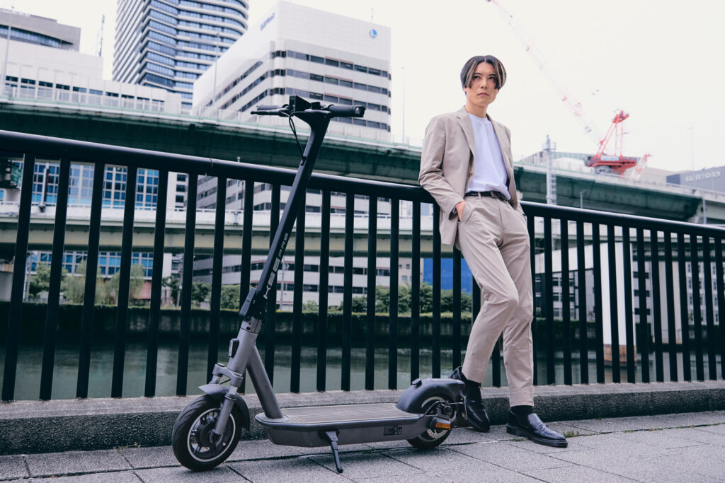 電動キックスケーターに寄りかかるスーツ姿の男性