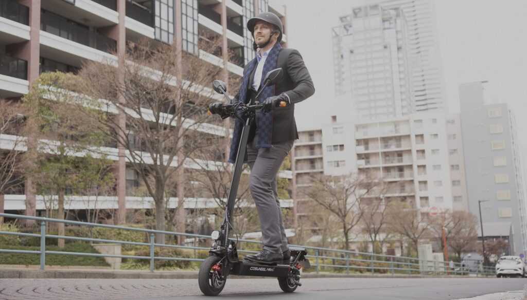 電動キックボードに乗るヘルメットをかぶった男性