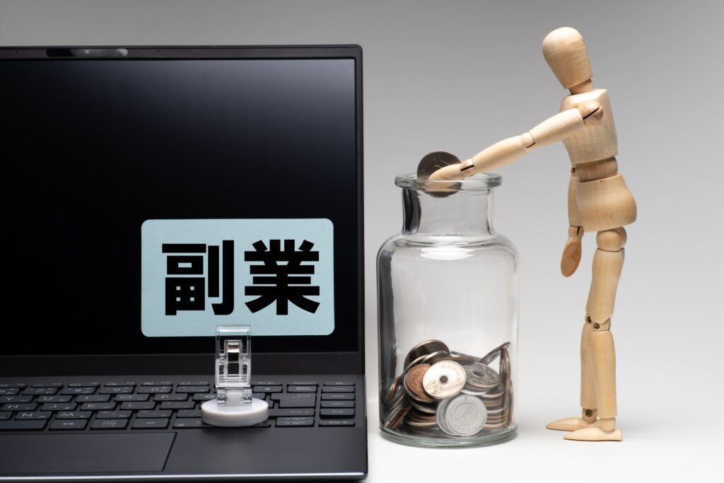 パソコンに副業と表示され貯金箱にコインを入れる人形