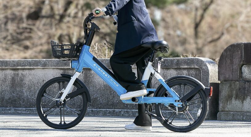 水色の電動アシスト自転車に乗る人の画像