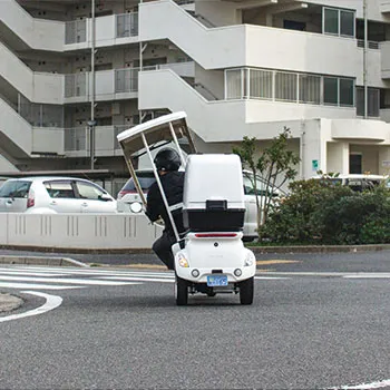 屋根付きの白い電動バイクに乗る人