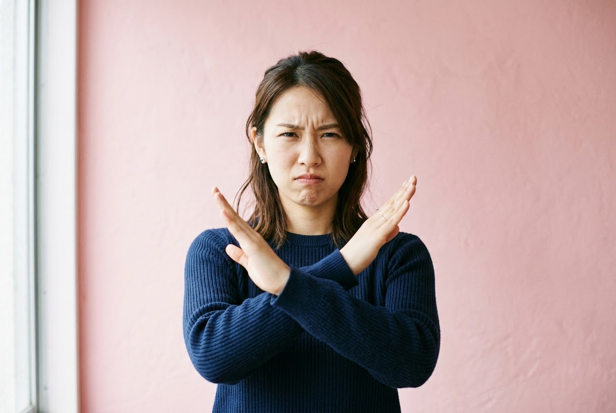 困った表情で腕をクロスさせ、電動キックボードの利用不可やトラブルに対して「ダメ」というポーズをとる女性。